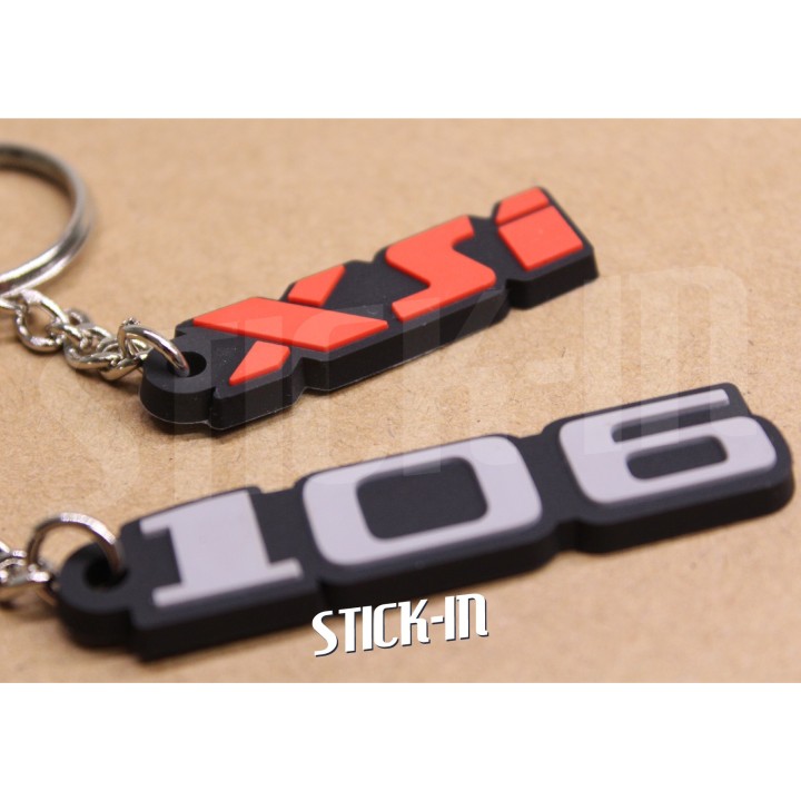 Pack de 2 llaveros Peugeot 106 + XSi de PVC blando con monogramas y logotipos.